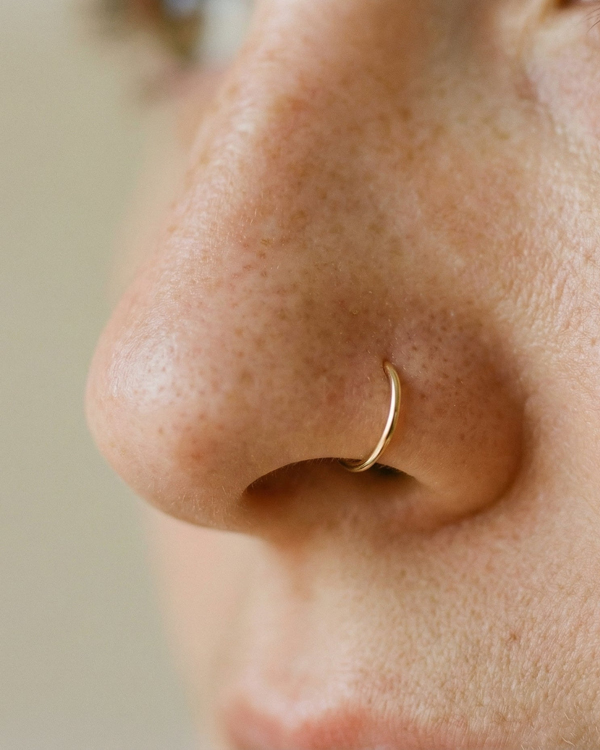 Close-up of a person wearing a gold nose ring with a blurred background