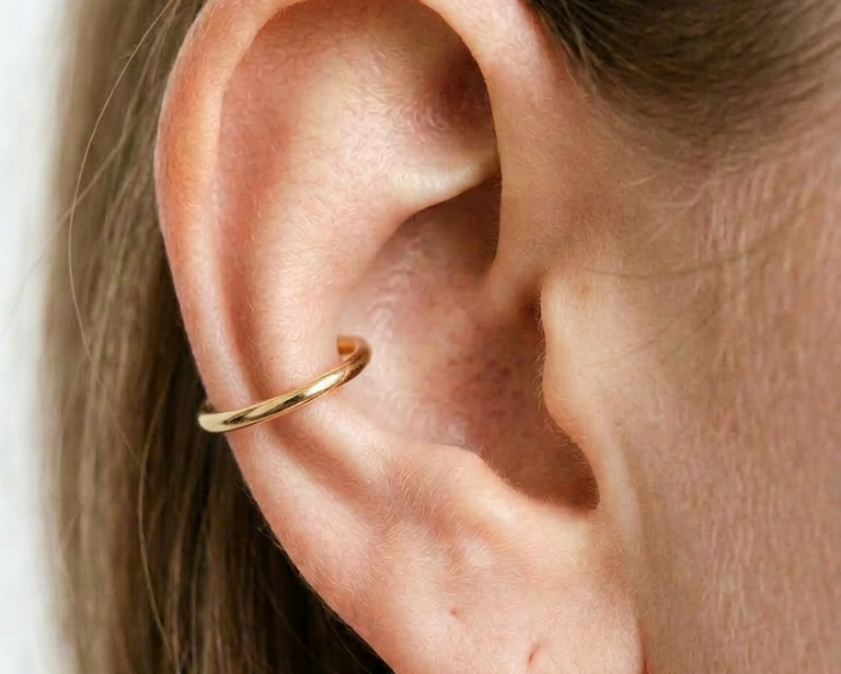 14K gold conch hoop earring close-up on ear