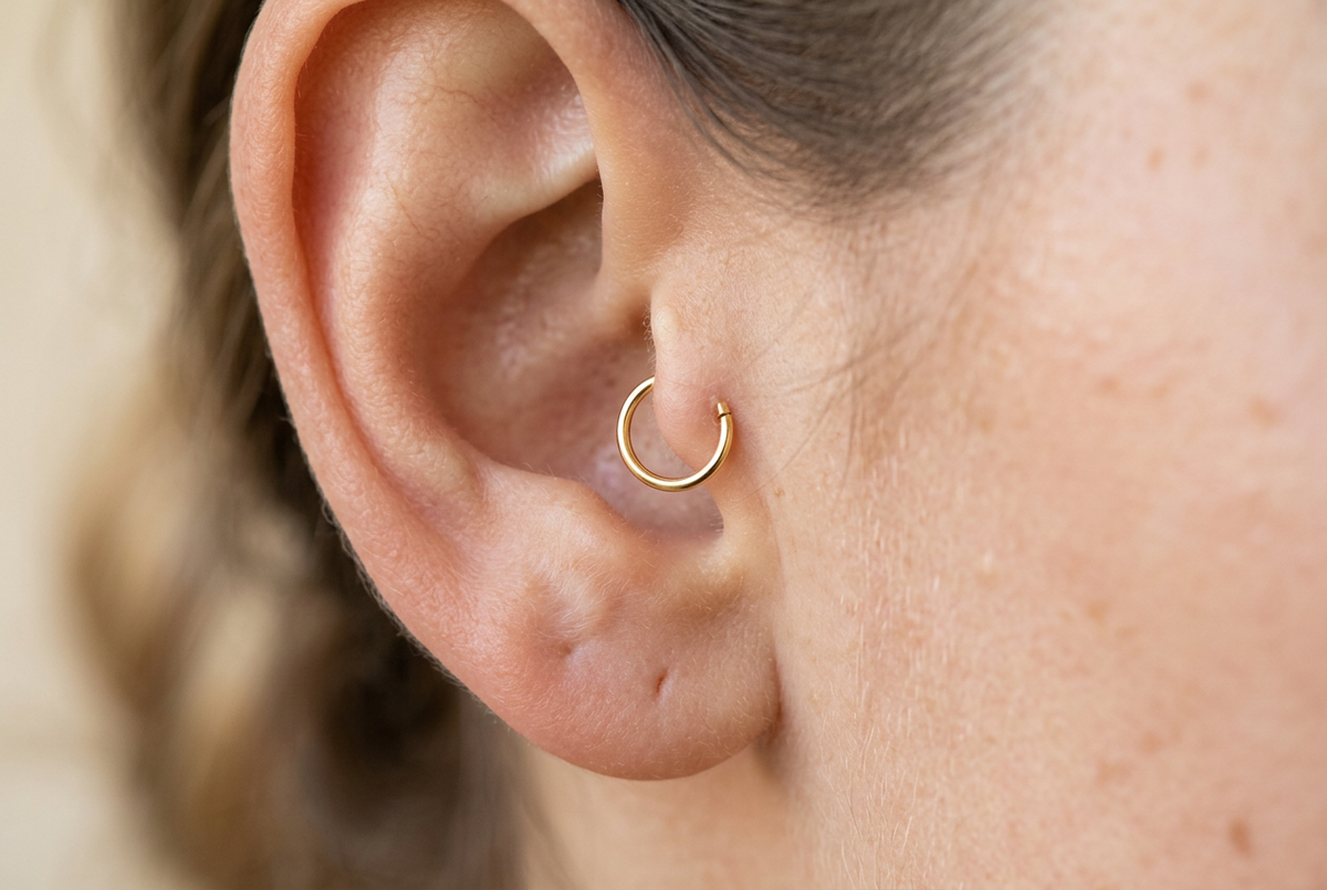 14K gold seamless hoop on a tragus piercing, close-up showing the small ring on the cartilage flap