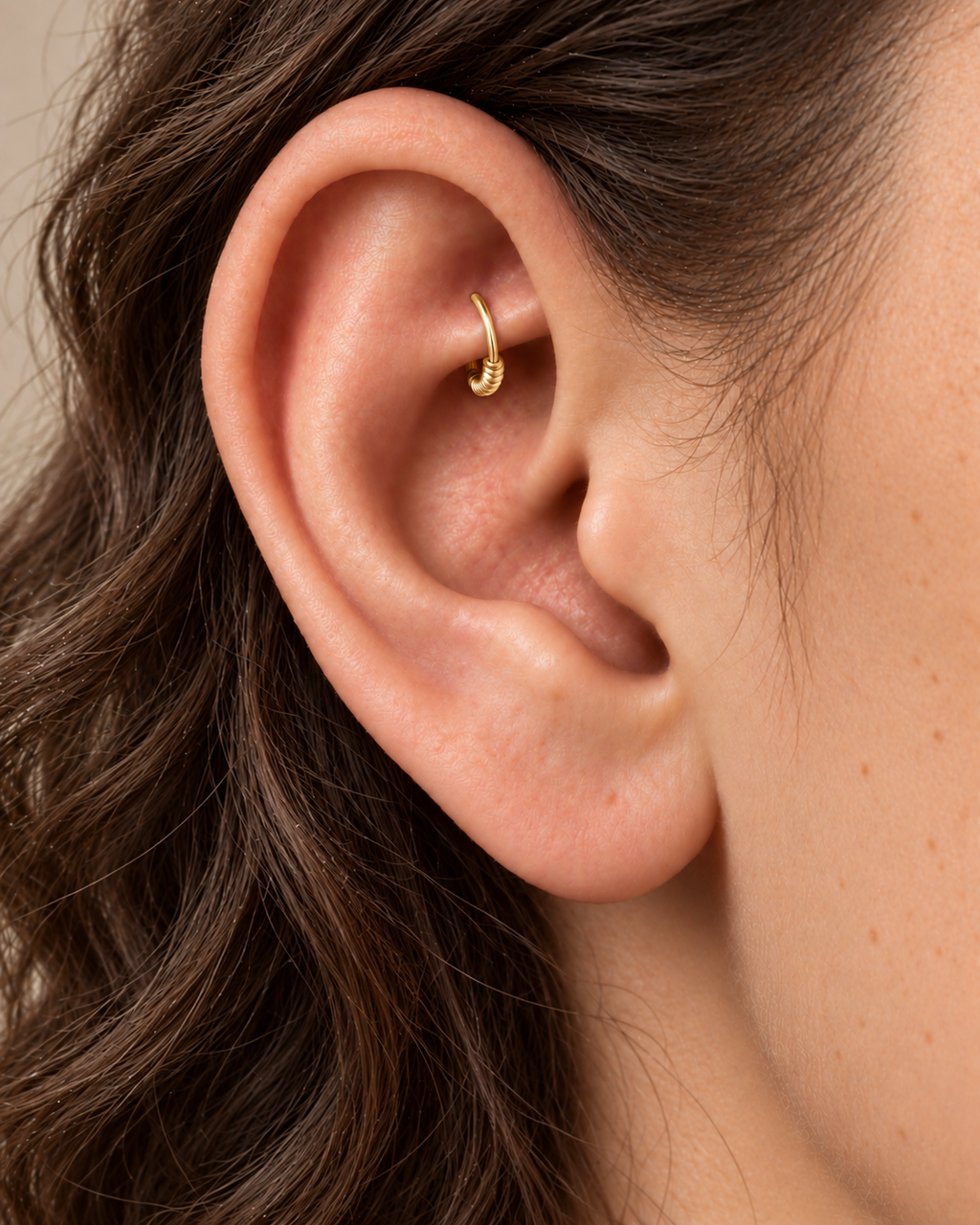 A little detail, tucked beneath the inner fold. Solis brings a softly wrapped lower curve to a delicate 14ct solid gold rook ring. Fine gold wire is wound by hand around approximately half the hoop, while the upper arc stays smooth and polished.