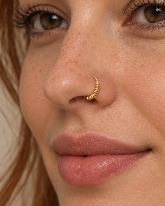 A little detail for your everyday nose ring. Solis brings a softly wrapped lower curve to a delicate 14ct solid gold nostril ring. Fine gold wire is wound by hand around approximately half the hoop, while the upper arc stays smooth and polished.