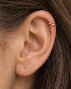 A polished ball adds a classic bead-like detail that works easily with simple solid-gold jewellery. Made for fully healed helix piercings, it keeps the profile compact for an upper-ear stack while leaving the motif clearly visible. Handmade to order in 14ct solid gold, it fits naturally with classic, polished and minimal styling rather than reading as a generic plain hoop.