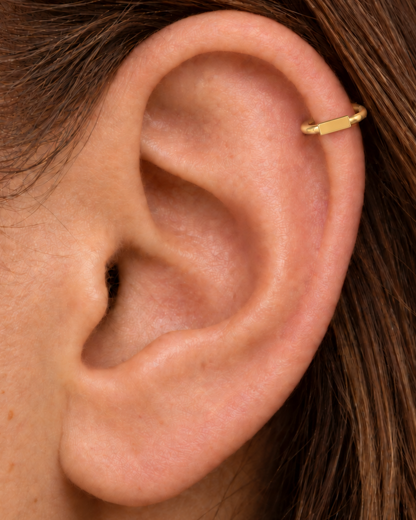 A slim bar creates a clean linear accent for a more modern, pared-back jewellery stack. Made for fully healed helix piercings, it keeps the profile compact for an upper-ear stack while leaving the motif clearly visible. Handmade to order in 14ct solid gold, it fits naturally with linear, minimal and modern styling rather than reading as a generic plain hoop.