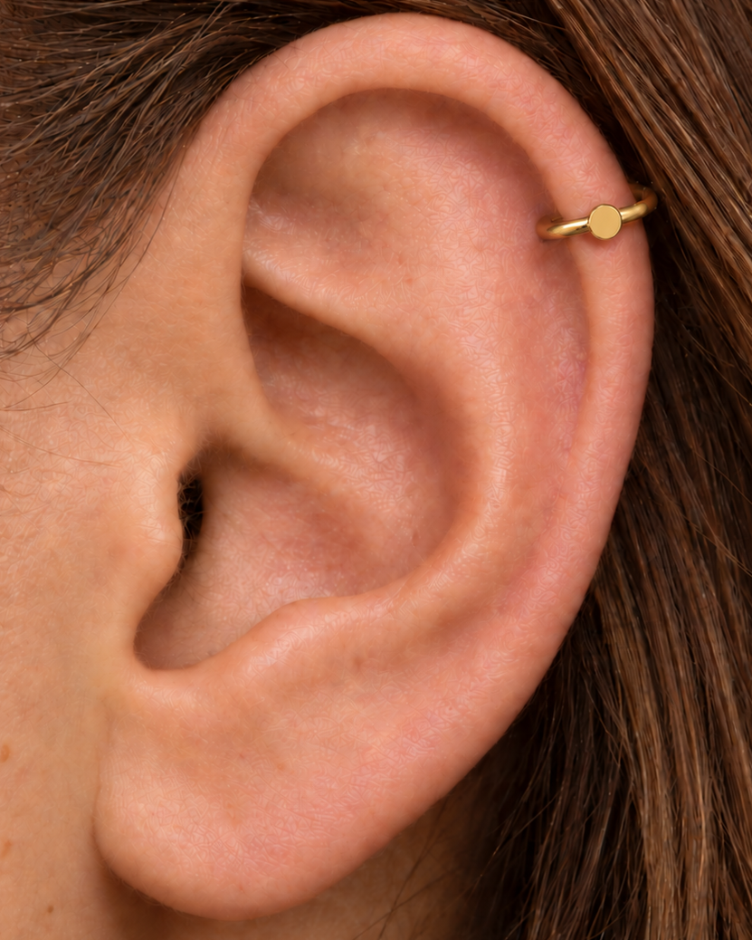 A simple circle motif keeps the design pared back, rounded and easy to mix with other jewellery. Made for fully healed helix piercings, it keeps the profile compact for an upper-ear stack while leaving the motif clearly visible. Handmade to order in 14ct solid gold, it fits naturally with simple, rounded and minimal styling rather than reading as a generic plain hoop.