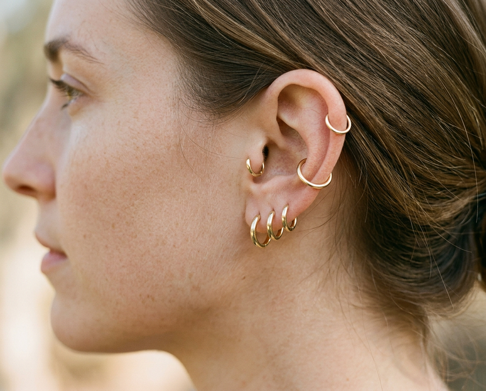 Complete curated ear stack showing 14K gold hoops and studs across lobe, helix, conch, and tragus piercings
