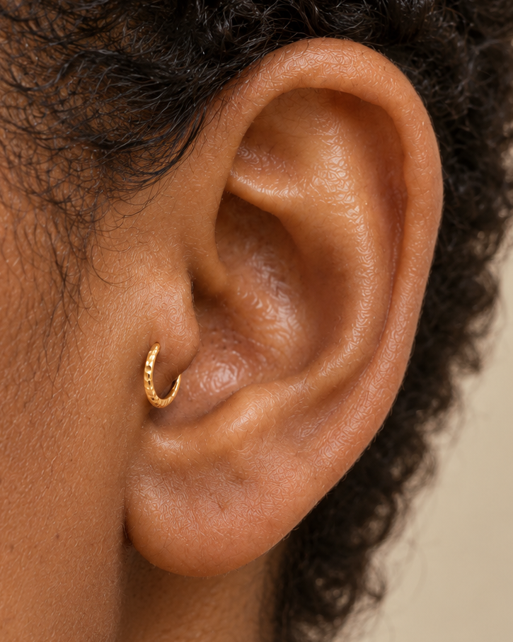 A small detail with its own quiet sparkle. Discover Glimmer, a 14ct solid gold tragus ring with a unique hand-hammered texture, handmade to order.