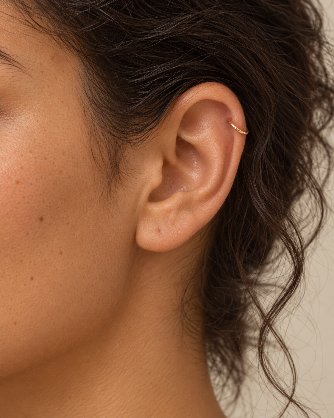 A small detail, tucked inside your ear. Ember brings a softly textured lower curve to a delicate 14ct solid gold daith ring. Its hand-hammered surface catches little flashes of light, while the upper arc stays smooth and polished.

We shape and hammer every ring individually, leaving a naturally uneven pattern that belongs to that piece alone. Choose a 6–10mm inner diameter, 18G or 20G, and yellow, white or rose gold. Handmade to order for fully healed daith piercings, with smooth round wire on both sides o