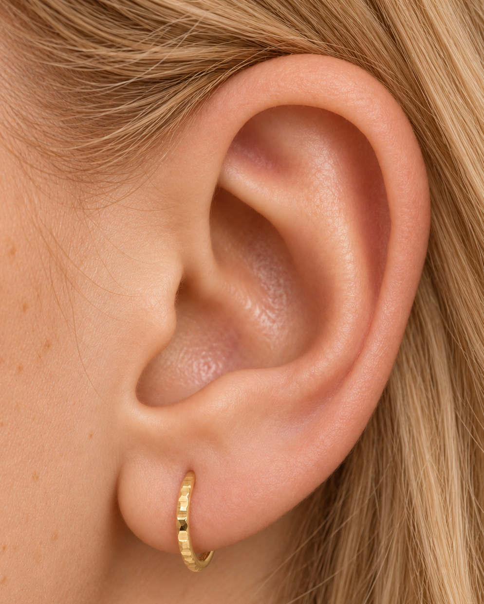 A familiar little hoop, with something extra to notice. Luma brings a softly shifting glow to a delicate 14ct solid gold earlobe hoop. The entire outer circumference is hammered by hand with tiny, irregular transverse marks: short strokes across the outer edge that catch the light in little flashes. The front-facing side and inner surface remain smooth and polished.

The width, depth, angle and spacing of these small marks vary naturally with each hammer stroke. No two rings have exactly the same pattern; y