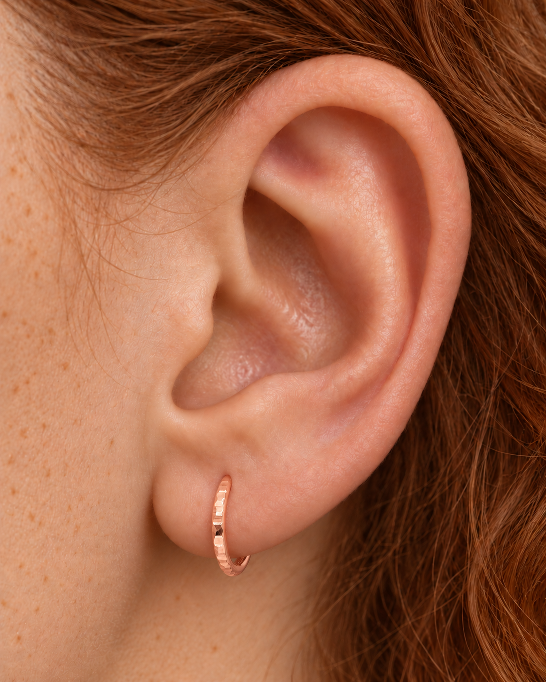 A familiar little hoop, with something extra to notice. Luma brings a softly shifting glow to a delicate 14ct solid gold earlobe hoop. The entire outer circumference is hammered by hand with tiny, irregular transverse marks: short strokes across the outer edge that catch the light in little flashes. The front-facing side and inner surface remain smooth and polished.

The width, depth, angle and spacing of these small marks vary naturally with each hammer stroke. No two rings have exactly the same pattern