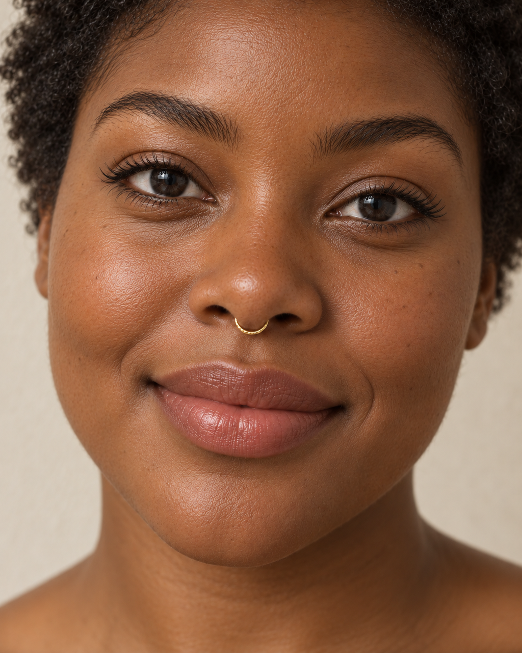 A little light beside your smile. Luma brings a softly shifting glow to a delicate 14ct solid gold nostril ring. The entire outer circumference is hammered by hand with tiny, irregular transverse marks: short strokes across the outer edge that catch the light in little flashes. The front-facing side and inner surface remain smooth and polished.

The width, depth, angle and spacing of these small marks vary naturally with each hammer stroke. No two rings have exactly the same pattern; yours will share the de