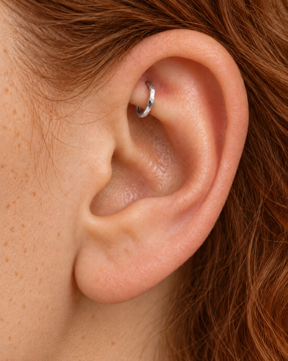 A quiet flash of gold in the upper fold of your ear. Luma brings a softly shifting glow to a delicate 14ct solid gold rook ring. The entire outer circumference is hammered by hand with tiny, irregular transverse marks: short strokes across the outer edge that catch the light in little flashes. The front-facing side and inner surface remain smooth and polished.