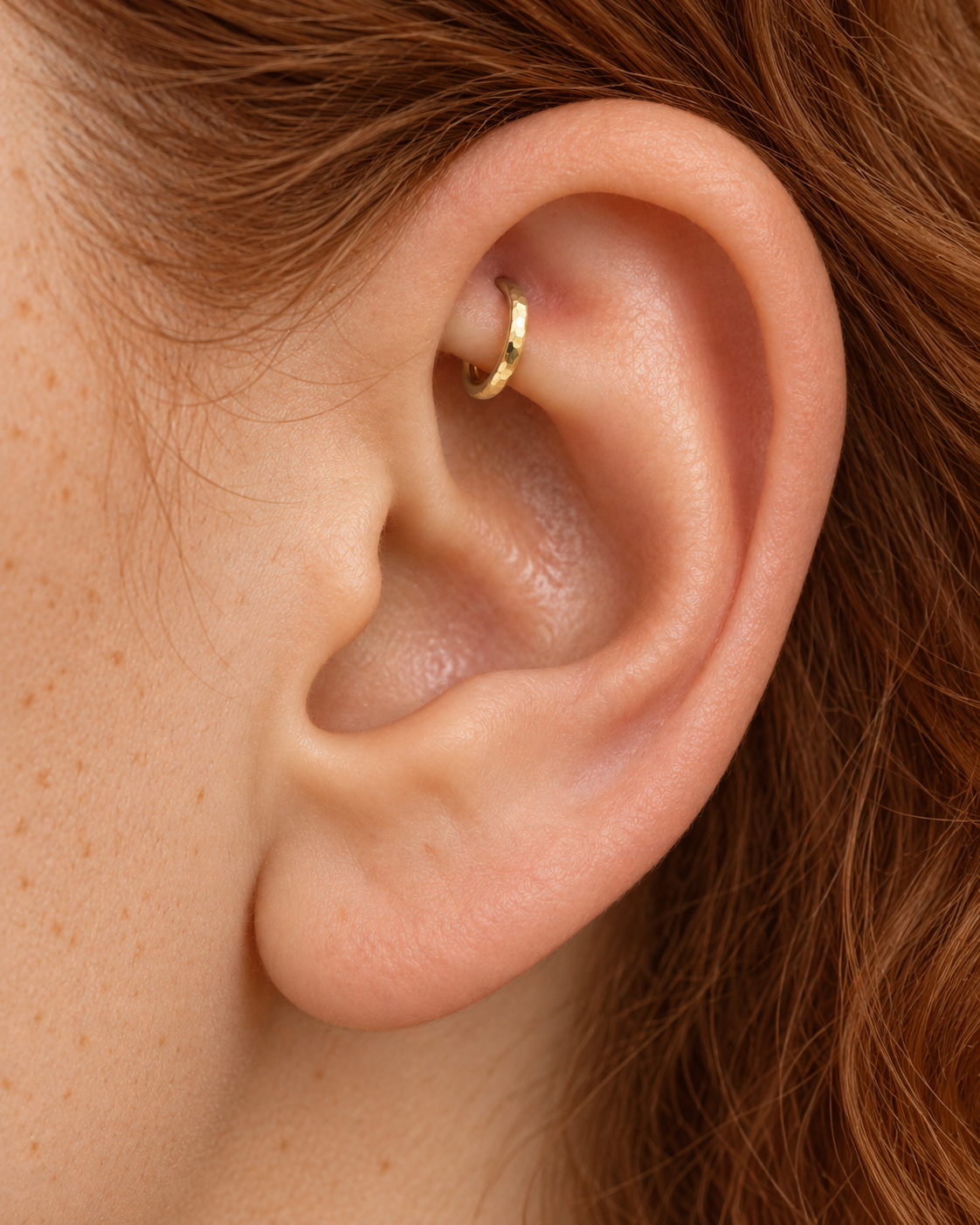 A quiet flash of gold in the upper fold of your ear. Luma brings a softly shifting glow to a delicate 14ct solid gold rook ring. The entire outer circumference is hammered by hand with tiny, irregular transverse marks: short strokes across the outer edge that catch the light in little flashes. The front-facing side and inner surface remain smooth and polished.
