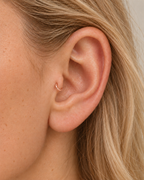 A tiny detail with a little light of its own. Luma brings a softly shifting glow to a delicate 14ct solid gold tragus ring. The entire outer circumference is hammered by hand with tiny, irregular transverse marks: short strokes across the outer edge that catch the light in little flashes. The front-facing side and inner surface remain smooth and polished.

The width, depth, angle and spacing of these small marks vary naturally with each hammer stroke. No two rings have exactly the same pattern; yours will s