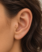 A tiny detail with a little light of its own. Luma brings a softly shifting glow to a delicate 14ct solid gold tragus ring. The entire outer circumference is hammered by hand with tiny, irregular transverse marks: short strokes across the outer edge that catch the light in little flashes. The front-facing side and inner surface remain smooth and polished.

The width, depth, angle and spacing of these small marks vary naturally with each hammer stroke. No two rings have exactly the same pattern; yours will s