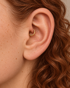 A small detail, tucked inside your ear. Ember brings a softly textured lower curve to a delicate 14ct solid gold daith ring. Its hand-hammered surface catches little flashes of light, while the upper arc stays smooth and polished.