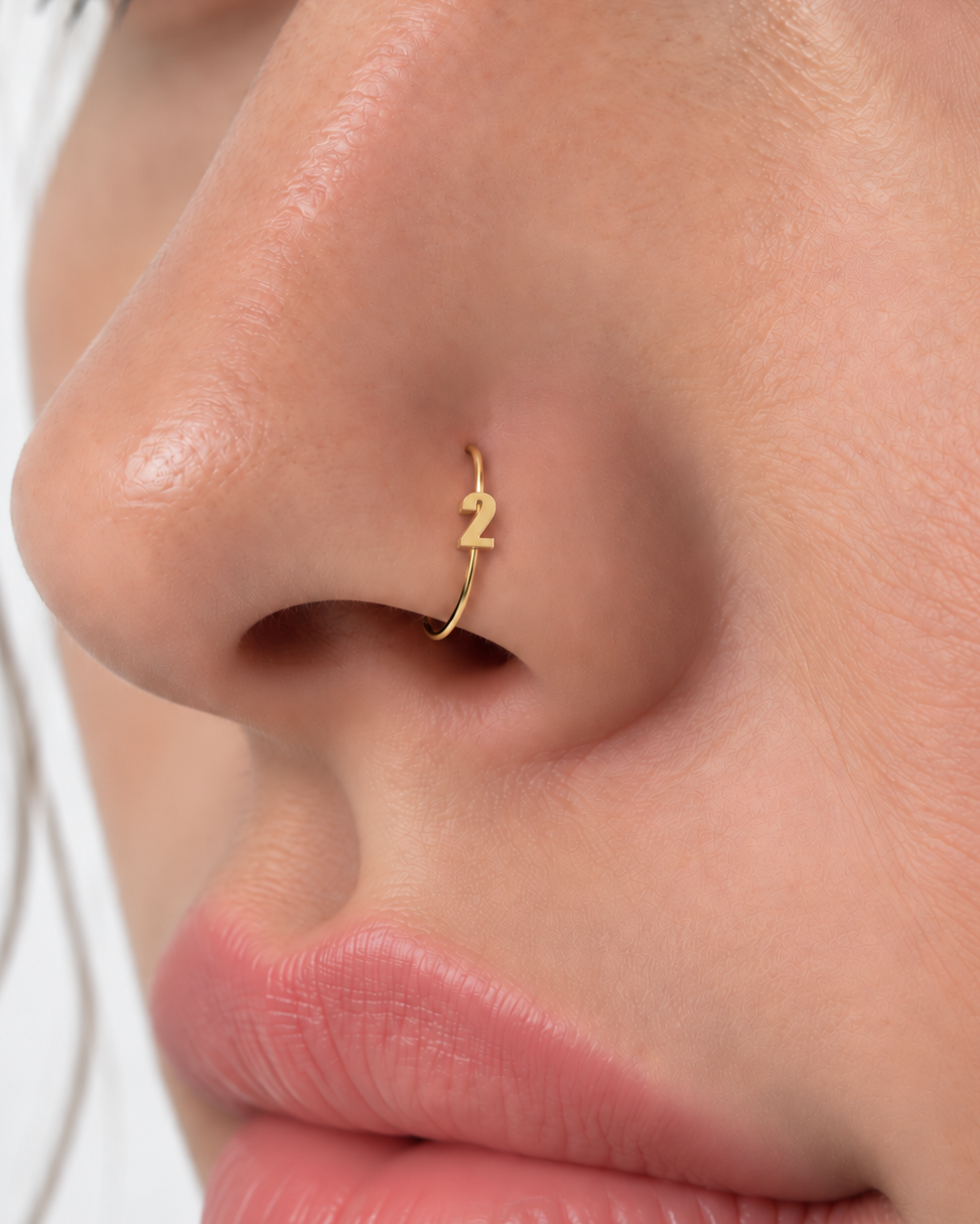 Choose one digit to give the hoop a small number-led detail with personal meaning. Made for fully healed nostril piercings, the motif sits directly on a clean round hoop so the look stays neat rather than dangly. Handmade to order in 14ct solid gold, it fits naturally with personalised, number-led and meaningful styling rather than reading as a generic plain hoop.