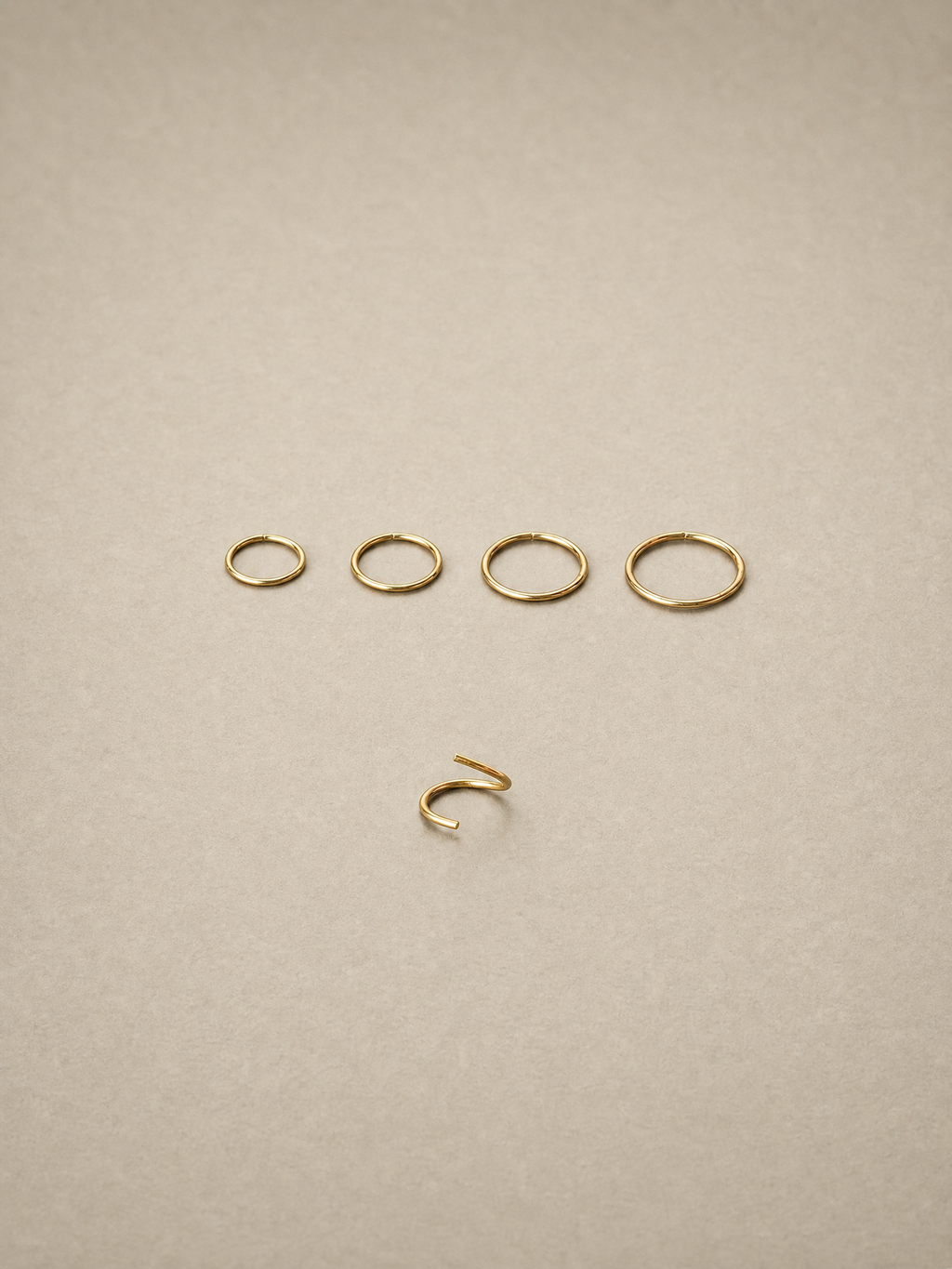 Set of 14ct gold ear seamless ring on a beige background