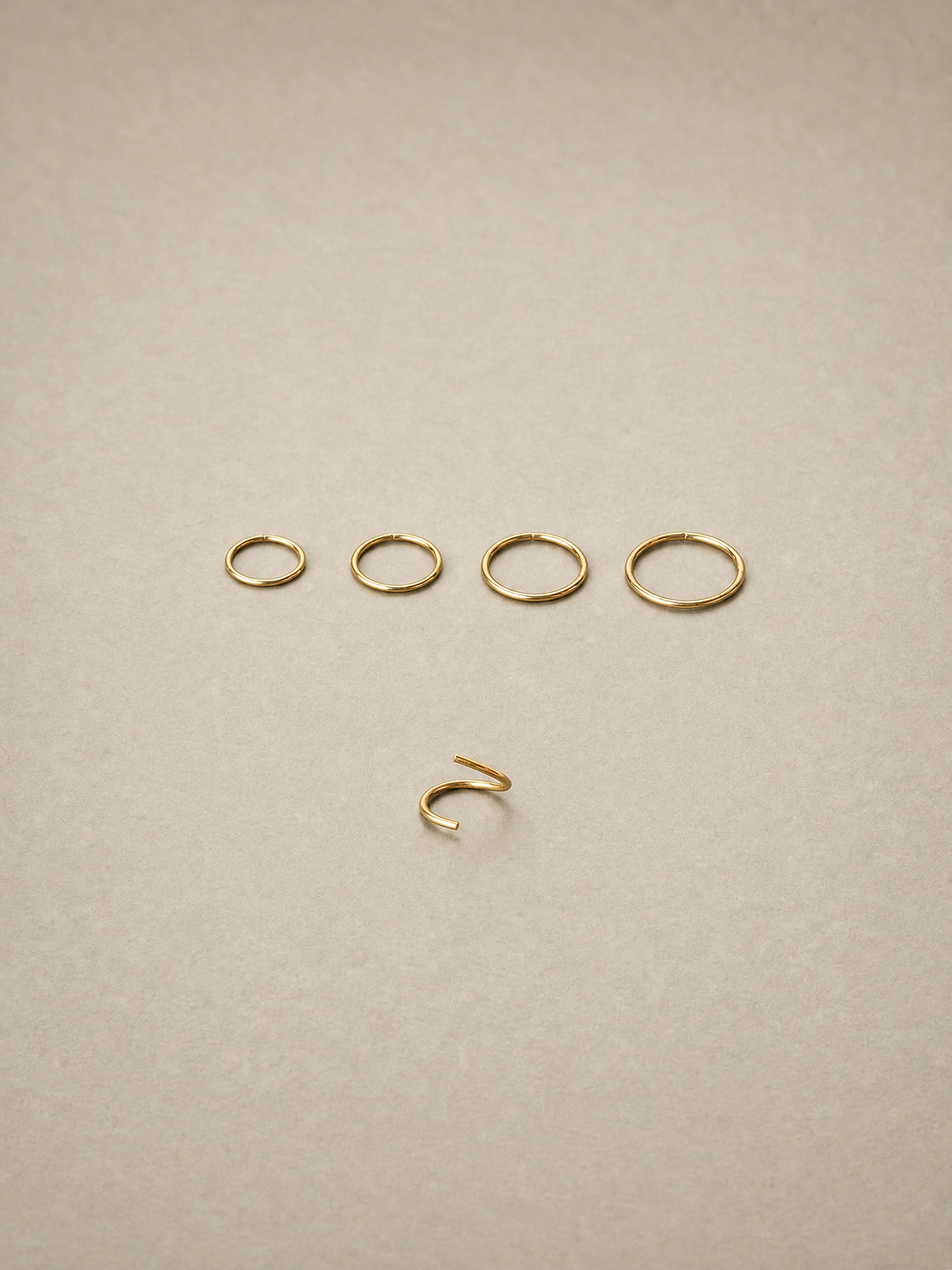 Set of 14ct gold ear seamless ring on a beige background