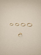 Set of 14ct gold ear seamless ring on a beige background