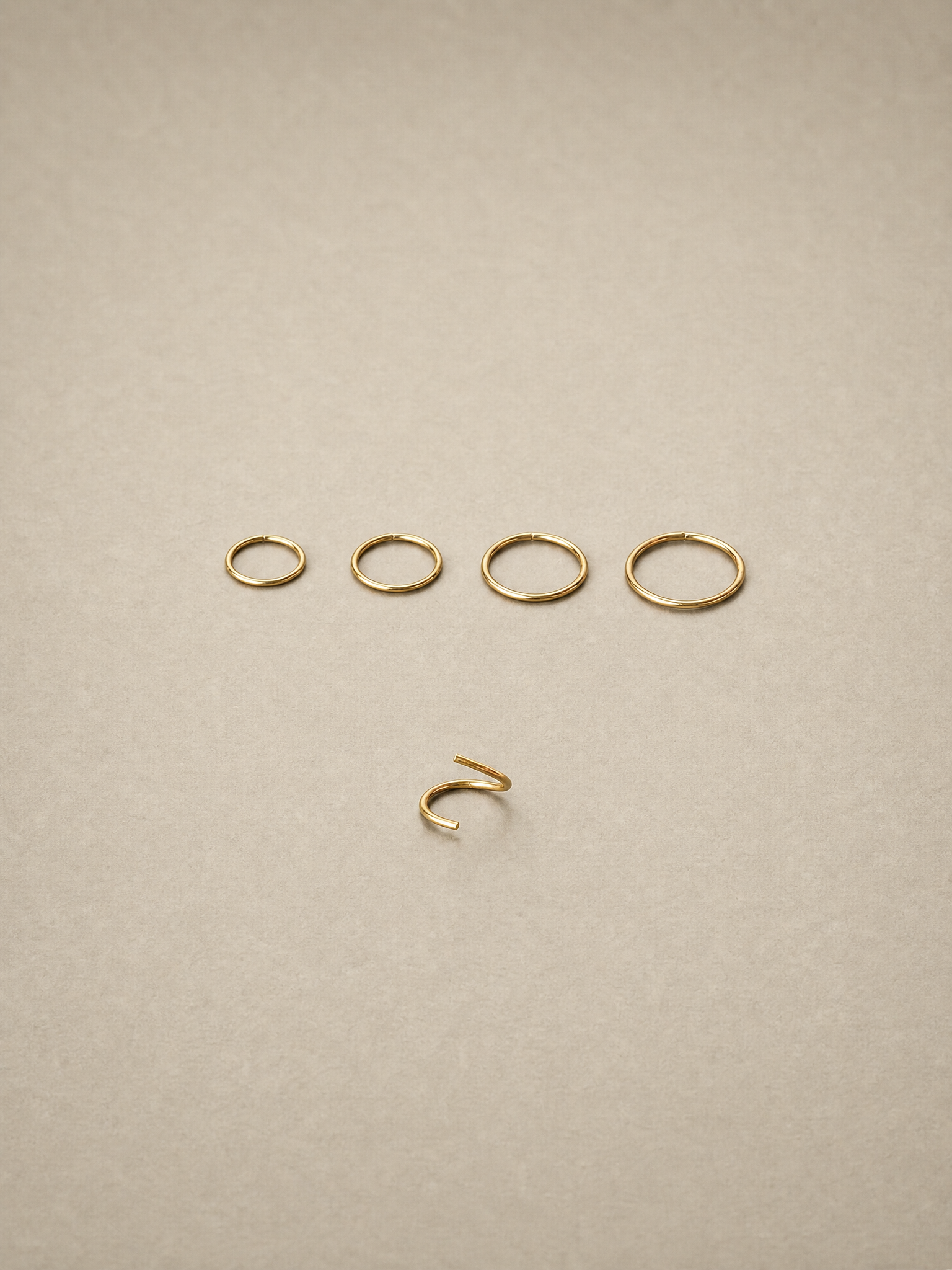 Set of 14ct gold ear seamless ring on a beige background