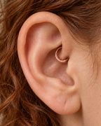 A small detail, tucked inside your ear. Solis brings a softly wrapped lower curve to a delicate 14ct solid gold daith ring. Fine gold wire is wound by hand around approximately half the hoop, while the upper arc stays smooth and polished.