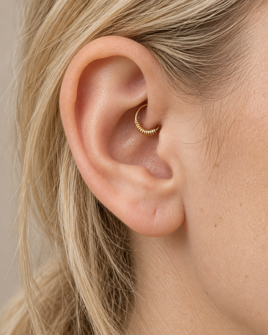 A small detail, tucked inside your ear. Solis brings a softly wrapped lower curve to a delicate 14ct solid gold daith ring. Fine gold wire is wound by hand around approximately half the hoop, while the upper arc stays smooth and polished.