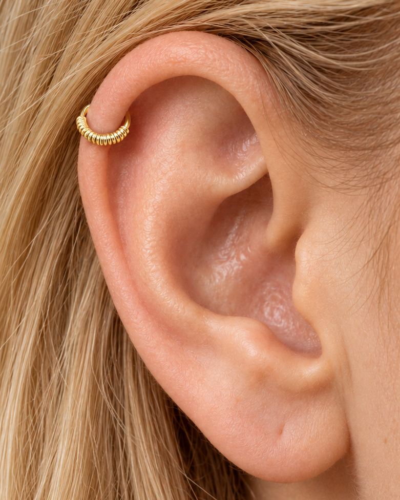A little detail along the curve of your ear. Solis brings a softly wrapped lower curve to a delicate 14ct solid gold helix ring. Fine gold wire is wound by hand around approximately half the hoop, while the upper arc stays smooth and polished.