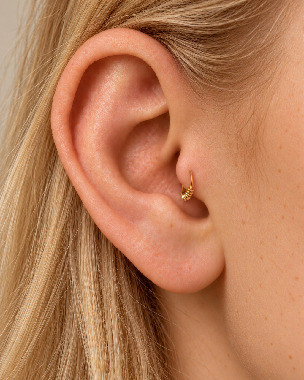 A small detail at the front of your ear. Solis brings a softly wrapped lower curve to a delicate 14ct solid gold tragus ring. Fine gold wire is wound by hand around approximately half the hoop, while the upper arc stays smooth and polished.