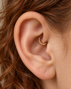 A small detail, tucked inside your ear. Solis brings a softly wrapped lower curve to a delicate 14ct solid gold daith ring. Fine gold wire is wound by hand around approximately half the hoop, while the upper arc stays smooth and polished.