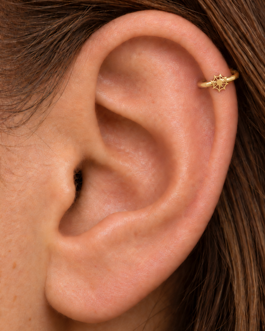 An openwork spider web adds a graphic Halloween detail with visible negative space and a light feel. Made for fully healed helix piercings, it keeps the profile compact for an upper-ear stack while leaving the motif clearly visible. Handmade to order in 14ct solid gold, it fits naturally with graphic, spooky and Halloween-led styling rather than reading as a generic plain hoop.