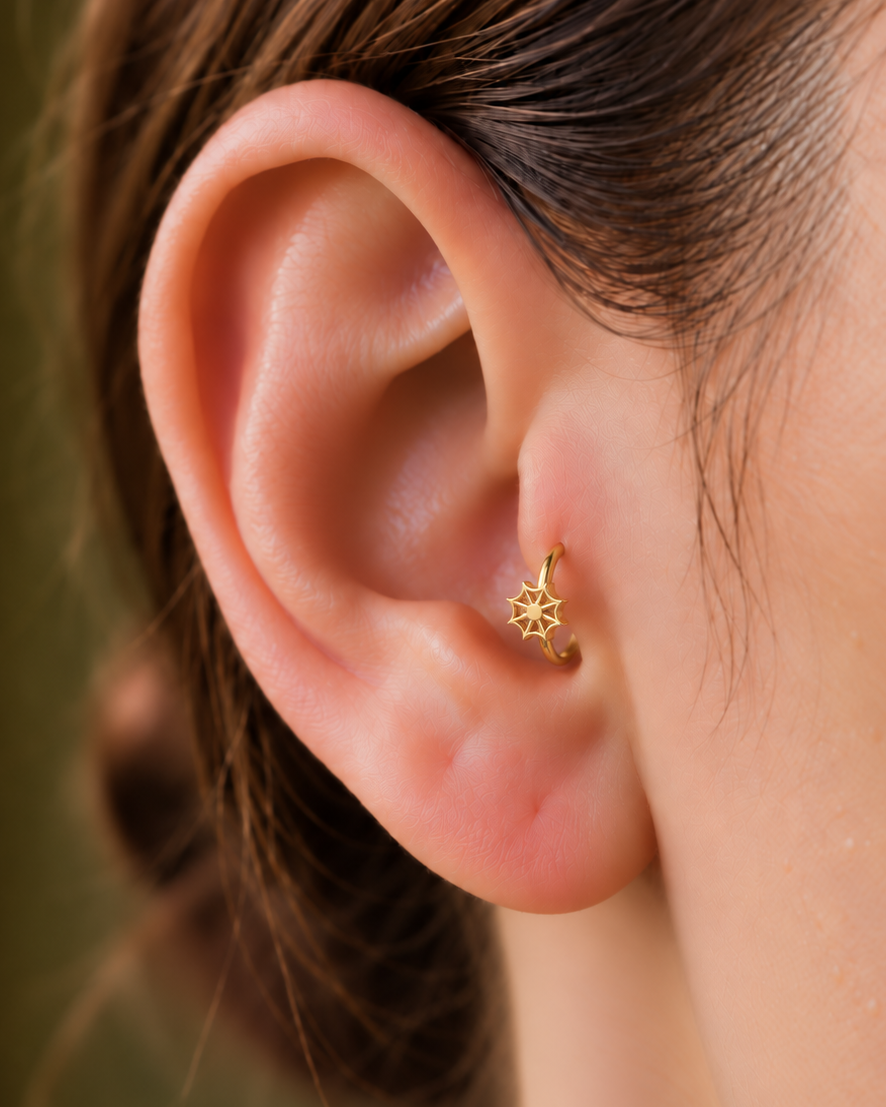 An openwork spider web adds a graphic Halloween detail with visible negative space and a light feel. Made for fully healed tragus piercings, it adds a compact decorative detail without turning the piece into a dangling design. Handmade to order in 14ct solid gold, it fits naturally with graphic, spooky and Halloween-led styling rather than reading as a generic plain hoop.