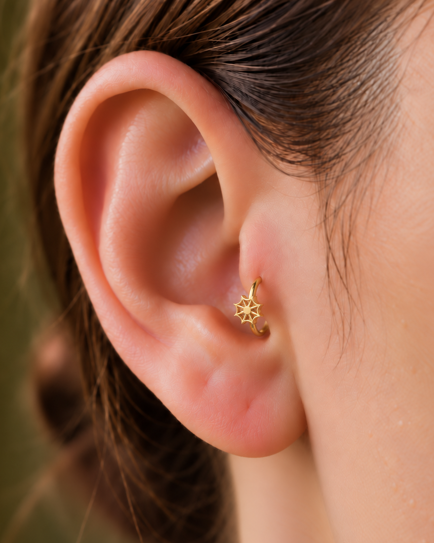 An openwork spider web adds a graphic Halloween detail with visible negative space and a light feel. Made for fully healed tragus piercings, it adds a compact decorative detail without turning the piece into a dangling design. Handmade to order in 14ct solid gold, it fits naturally with graphic, spooky and Halloween-led styling rather than reading as a generic plain hoop.