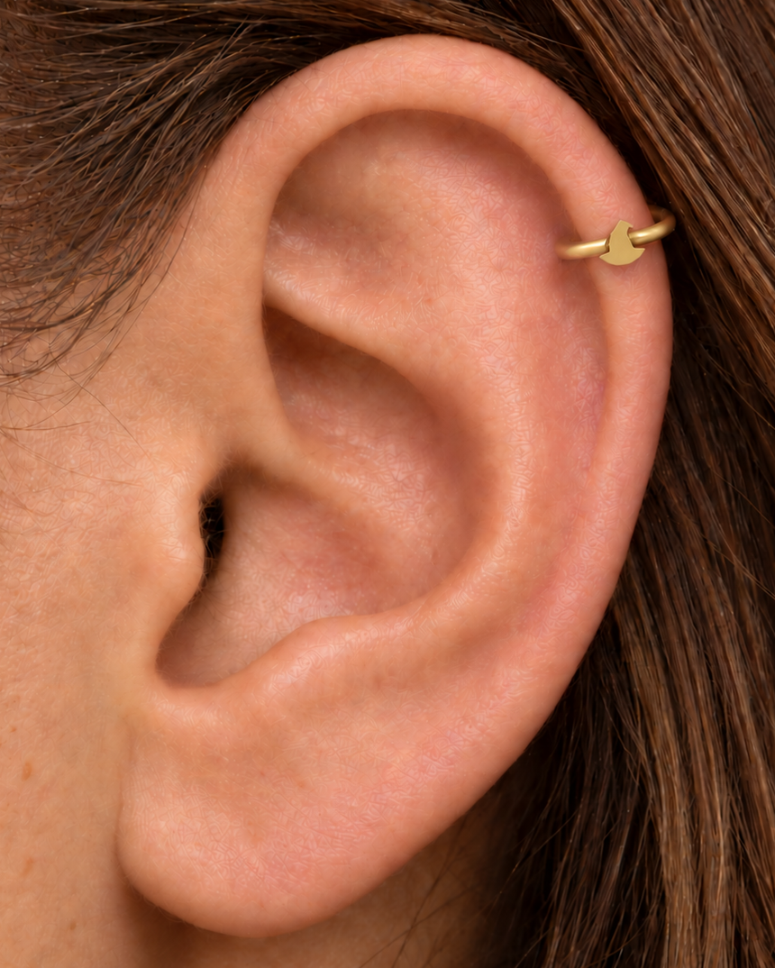 A tiny witch hat brings a playful witchy detail to the hoop without turning it into costume jewellery. Made for fully healed helix piercings, it keeps the profile compact for an upper-ear stack while leaving the motif clearly visible. Handmade to order in 14ct solid gold, it fits naturally with witchy, playful and Halloween-led styling rather than reading as a generic plain hoop.