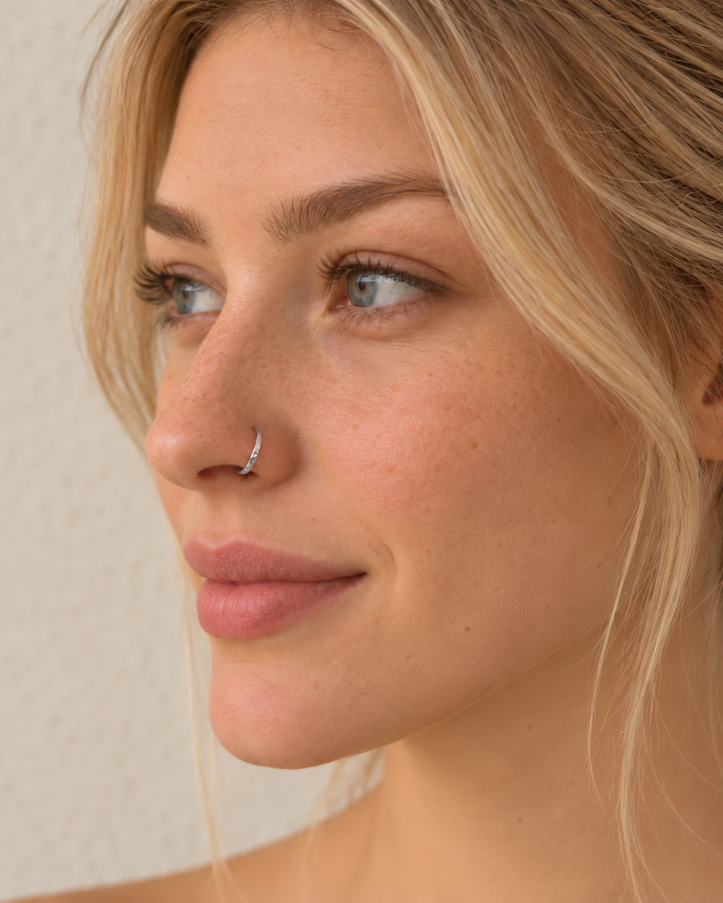A delicate 14ct solid gold seamless nostril hoop with a hand-hammered outer curve. Made to order in 6–10mm, 18G or 20G, in yellow, white or rose gold.