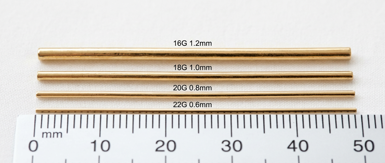 Four 14K gold seamless hoop wires showing 16G, 18G, 20G, and 22G thickness comparison side by side on a millimetre ruler