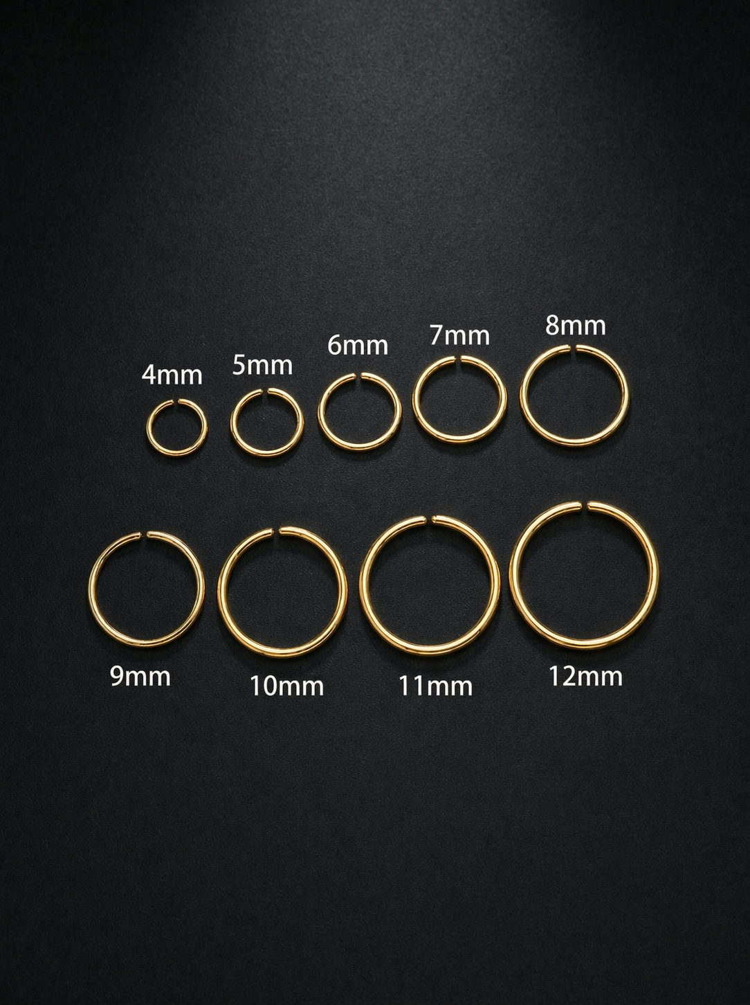 Set of gold hoop earrings in various sizes on a black background