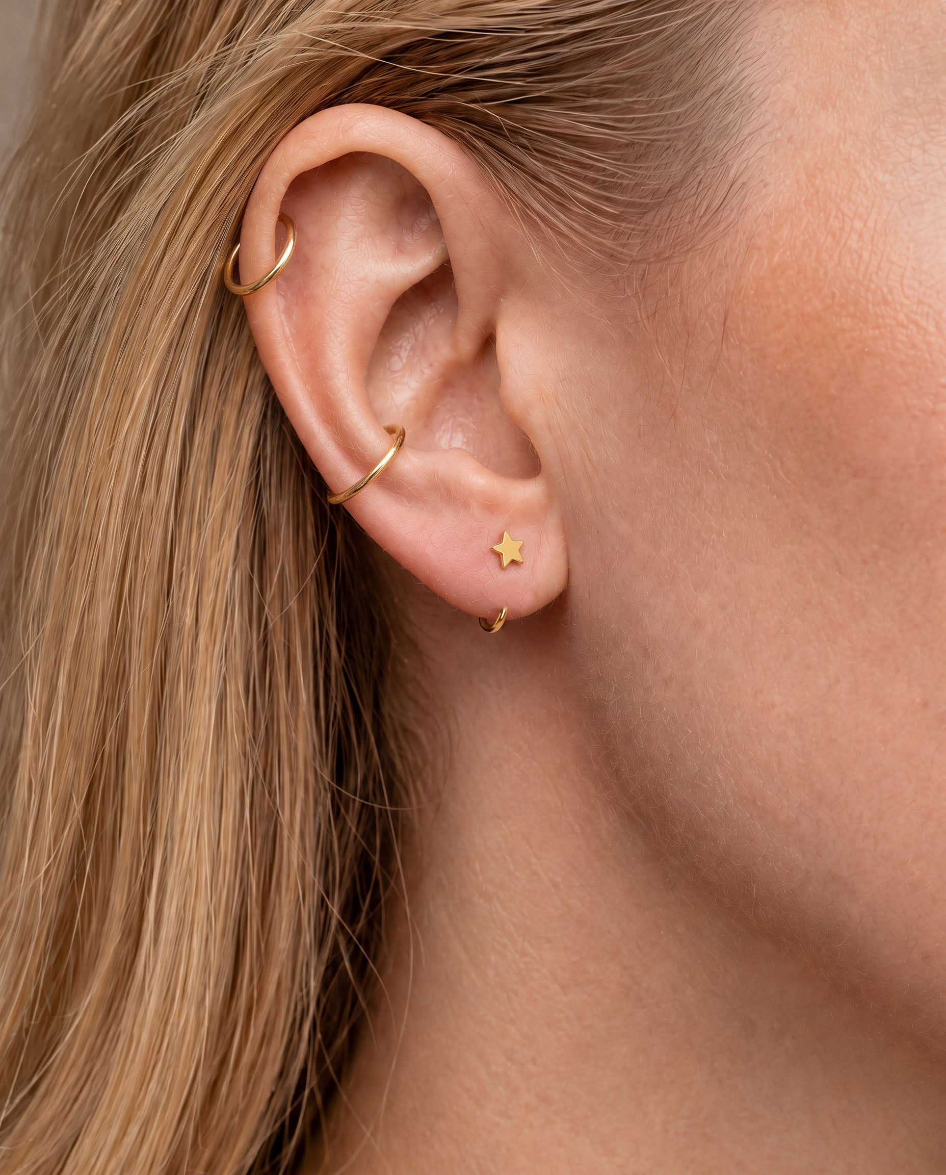 A playful 14ct solid gold star huggie hoop with an open design for easier fitting. No twisting or end alignment required — simply guide the smooth end through your fully healed nose or ear piercing and rotate it into position.