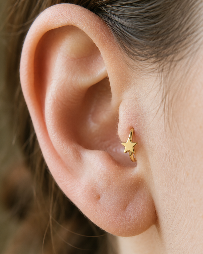 A crisp little star adds a bright celestial point to an otherwise minimal gold hoop. Made for fully healed tragus piercings, it adds a compact decorative detail without turning the piece into a dangling design. Handmade to order in 14ct solid gold, it fits naturally with bright, celestial and playful styling rather than reading as a generic plain hoop.