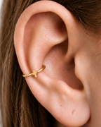 A polished cross gives the hoop a clean symbolic detail without stones, enamel or dangling parts. Made for fully healed conch piercings, it pairs the larger hoop silhouette of a conch ring with a small fixed motif for a more distinctive ear stack. Handmade to order in 14ct solid gold, it fits naturally with clean, symbolic and understated styling rather than reading as a generic plain hoop.