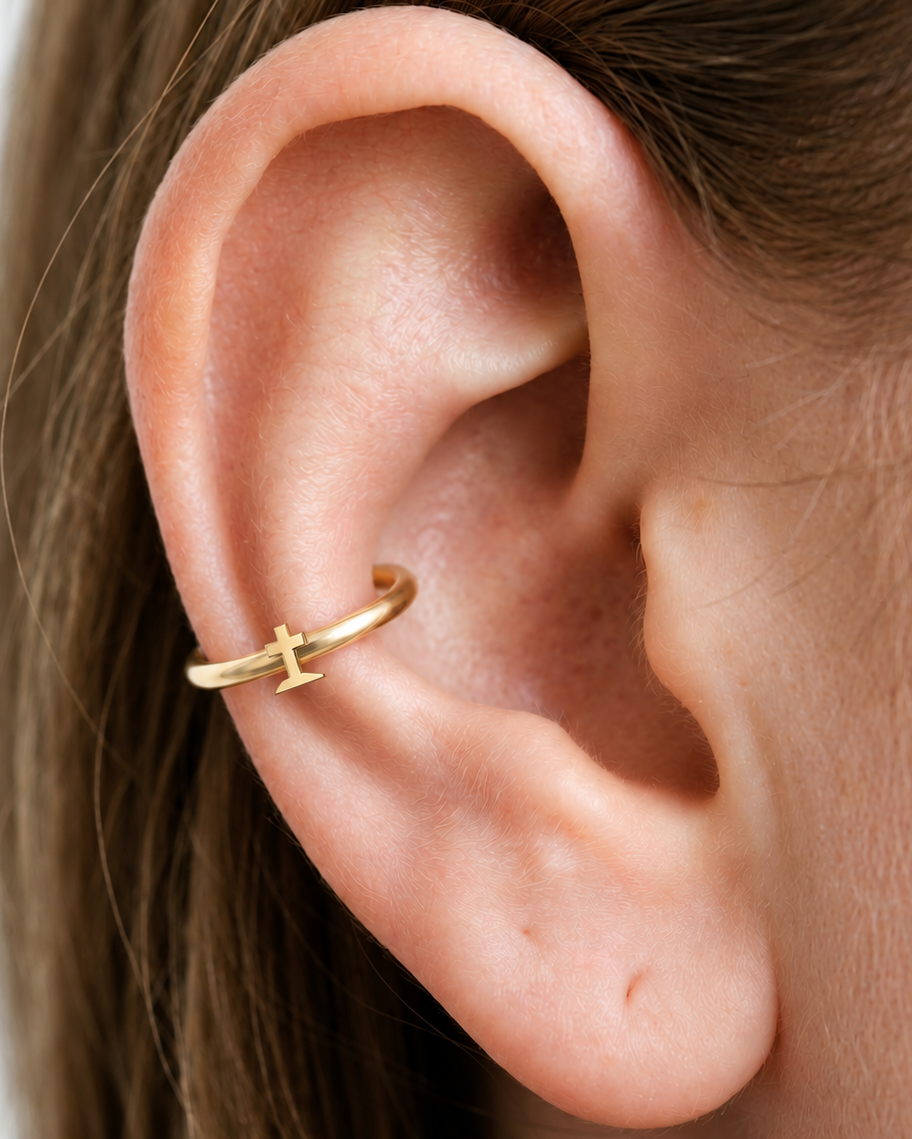 A graveyard-style cross gives the hoop a darker gothic reference that is distinct from the simpler cross design. Made for fully healed conch piercings, it pairs the larger hoop silhouette of a conch ring with a small fixed motif for a more distinctive ear stack. Handmade to order in 14ct solid gold, it fits naturally with gothic, spooky and alternative styling rather than reading as a generic plain hoop.