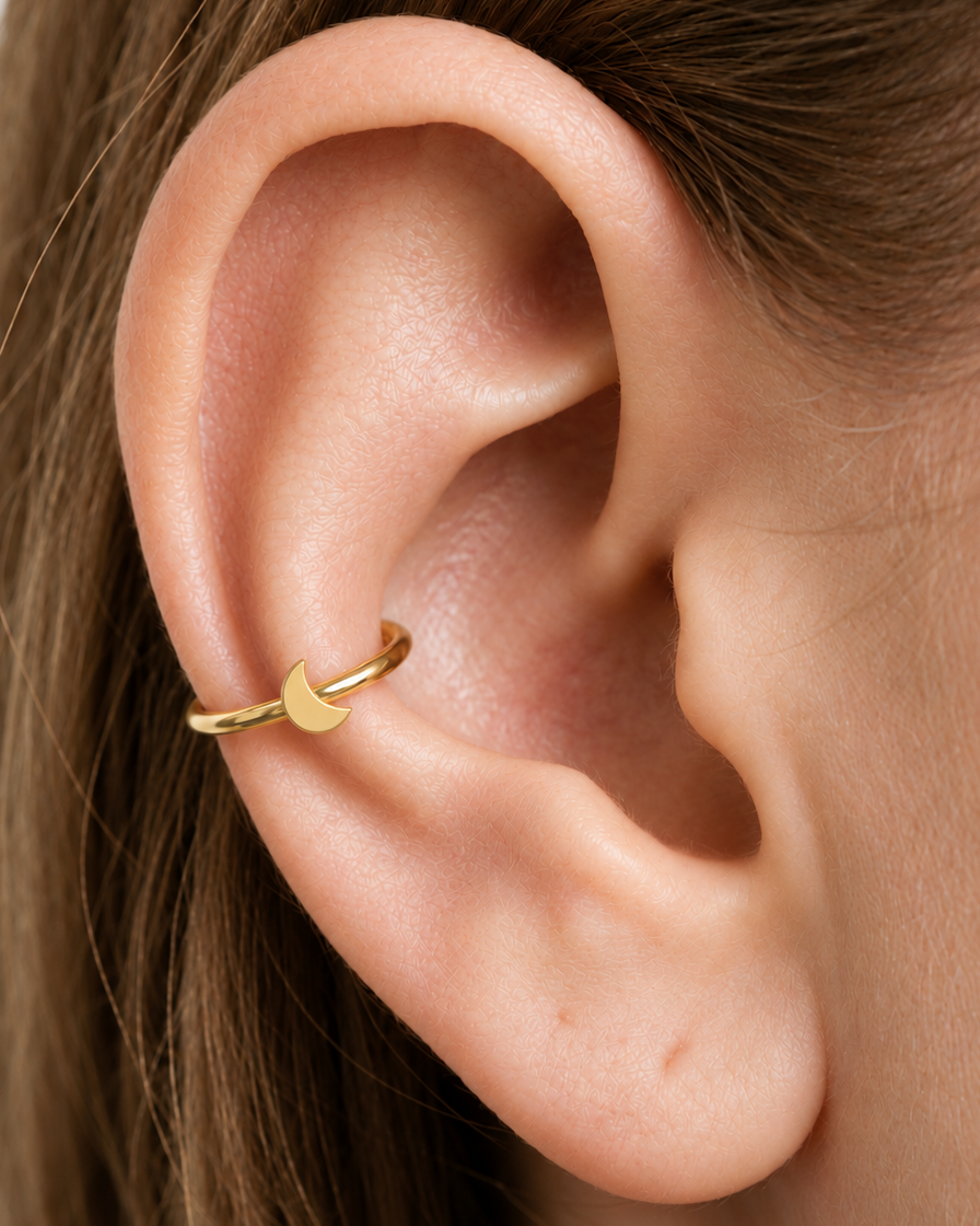 A small crescent moon gives the hoop a subtle celestial character with a polished solid-gold finish. Made for fully healed conch piercings, it pairs the larger hoop silhouette of a conch ring with a small fixed motif for a more distinctive ear stack. Handmade to order in 14ct solid gold, it fits naturally with celestial, lunar and softly symbolic styling rather than reading as a generic plain hoop.