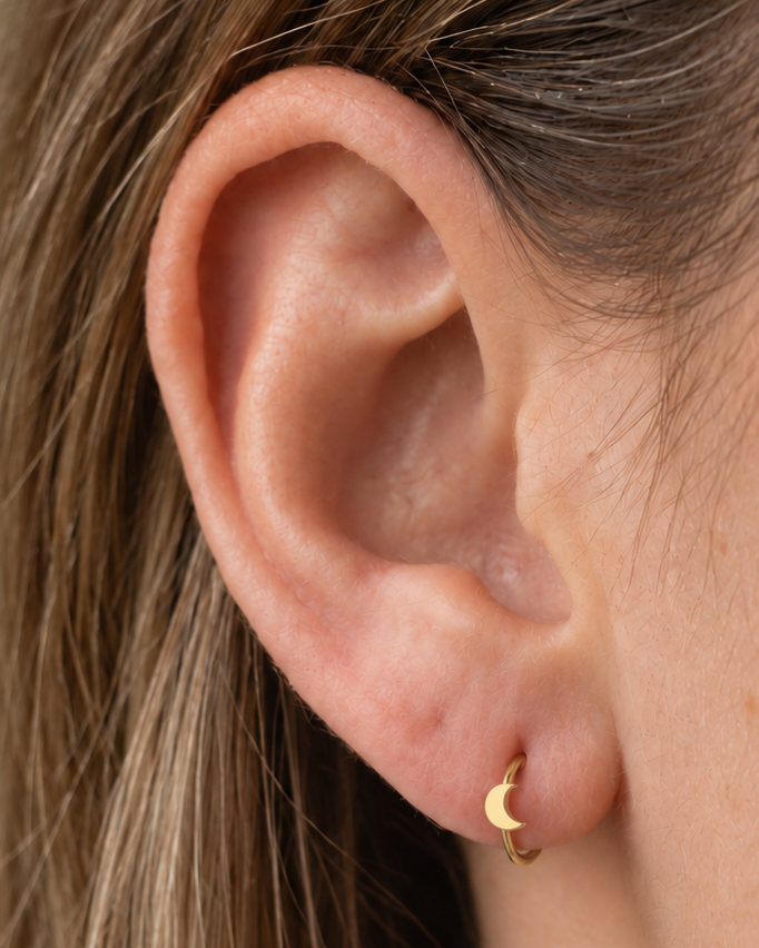 A small crescent moon gives the hoop a subtle celestial character with a polished solid-gold finish. Made for fully healed lobe piercings and sold individually, it works easily in first, second or third-lobe stacks. Handmade to order in 14ct solid gold, it fits naturally with celestial, lunar and softly symbolic styling rather than reading as a generic plain hoop.