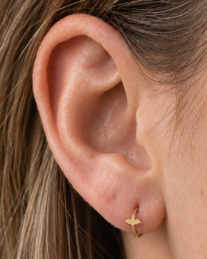 A small bat silhouette gives the hoop a sharper Halloween edge that can also work with gothic styling. Made for fully healed lobe piercings and sold individually, it works easily in first, second or third-lobe stacks. Handmade to order in 14ct solid gold, it fits naturally with spooky, gothic and Halloween-led styling rather than reading as a generic plain hoop.