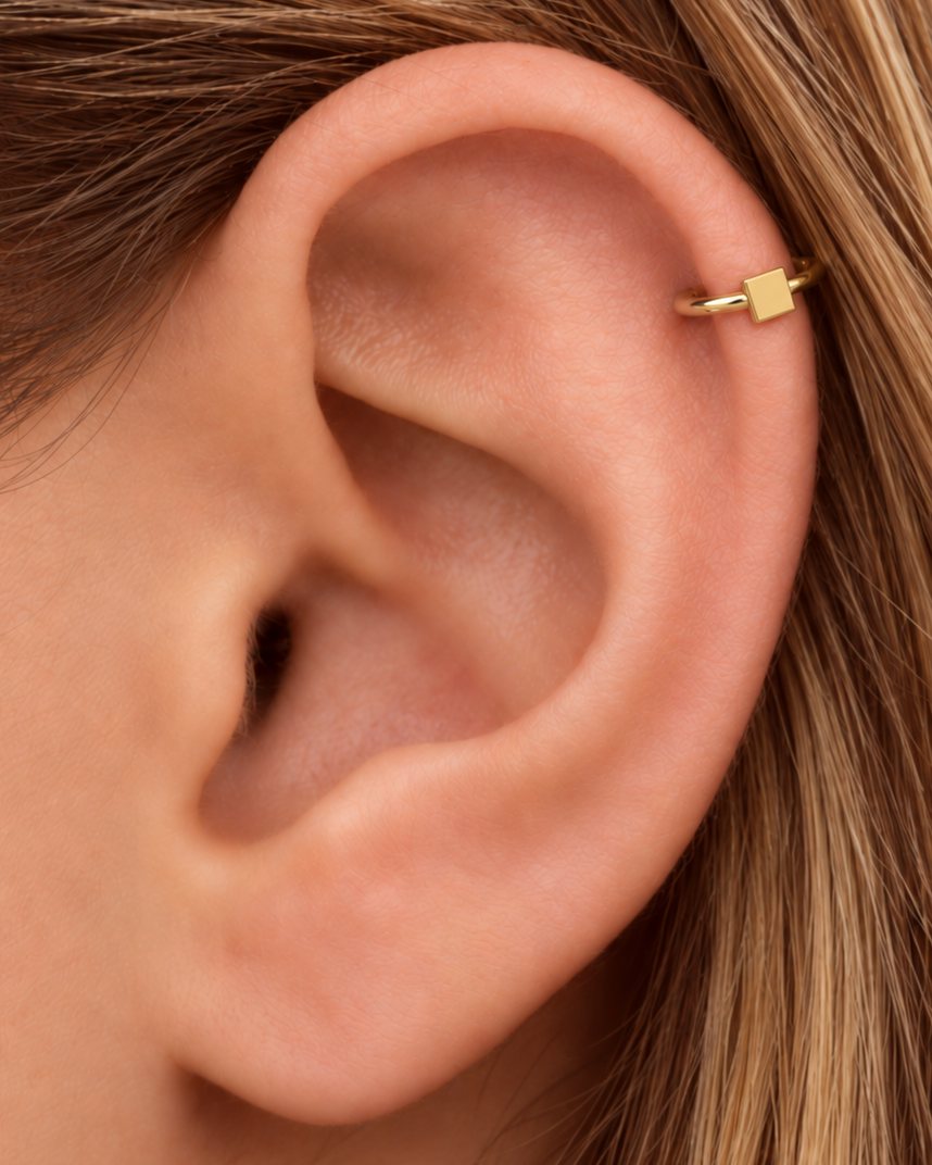 A small square motif gives the hoop a crisp, graphic finish while keeping the overall design minimal. Made for fully healed helix piercings, it keeps the profile compact for an upper-ear stack while leaving the motif clearly visible. Handmade to order in 14ct solid gold, it fits naturally with crisp, geometric and minimal styling rather than reading as a generic plain hoop.