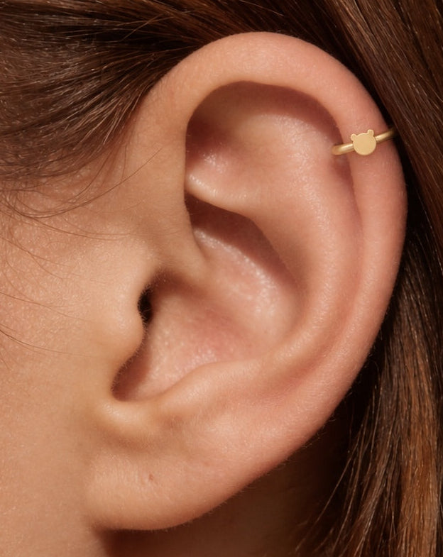This miniature bear head has two rounded ears and a smooth, gently curved face. Its polished surface has no engraved eyes or nose and no gemstones, keeping the outline clear and minimal.

Handmade to order in nickel-free 14ct solid gold, this bear helix hoop is available in yellow, white or rose gold. Choose a 5, 6 or 7mm internal diameter and 18G (1.0mm) or 20G (0.8mm). The motif measures approximately 3mm. Designed for fully healed helix piercings, with sizing chosen to suit your piercing position and ear
