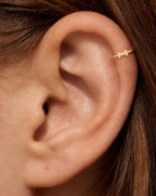 This miniature bow tie has two flared sides joined by a small central knot. Rounded outer corners soften its geometric outline, while the smooth gold surface keeps the design minimal. There are no trailing ribbon ends, engraved details or gemstones.

Handmade to order in nickel-free 14ct solid gold, this bow tie helix hoop is available in yellow, white or rose gold. Choose a 5, 6 or 7mm internal diameter and 18G (1.0mm) or 20G (0.8mm). The motif measures approximately 3mm. Designed for fully healed helix pi