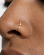 This miniature snowflake has six arms radiating from a solid centre, each with small branches and rounded ends. The spaces between the arms define the shape, while the smooth gold surface keeps the design simple. There are no gemstones or engraved details.

Handmade to order in nickel-free 14ct solid gold, this snowflake nostril hoop is available in yellow, white or rose gold. Choose a 6, 7, 8, 9 or 10mm internal diameter and 18G (1.0mm) or 20G (0.8mm). The motif measures approximately 3mm. Designed for ful