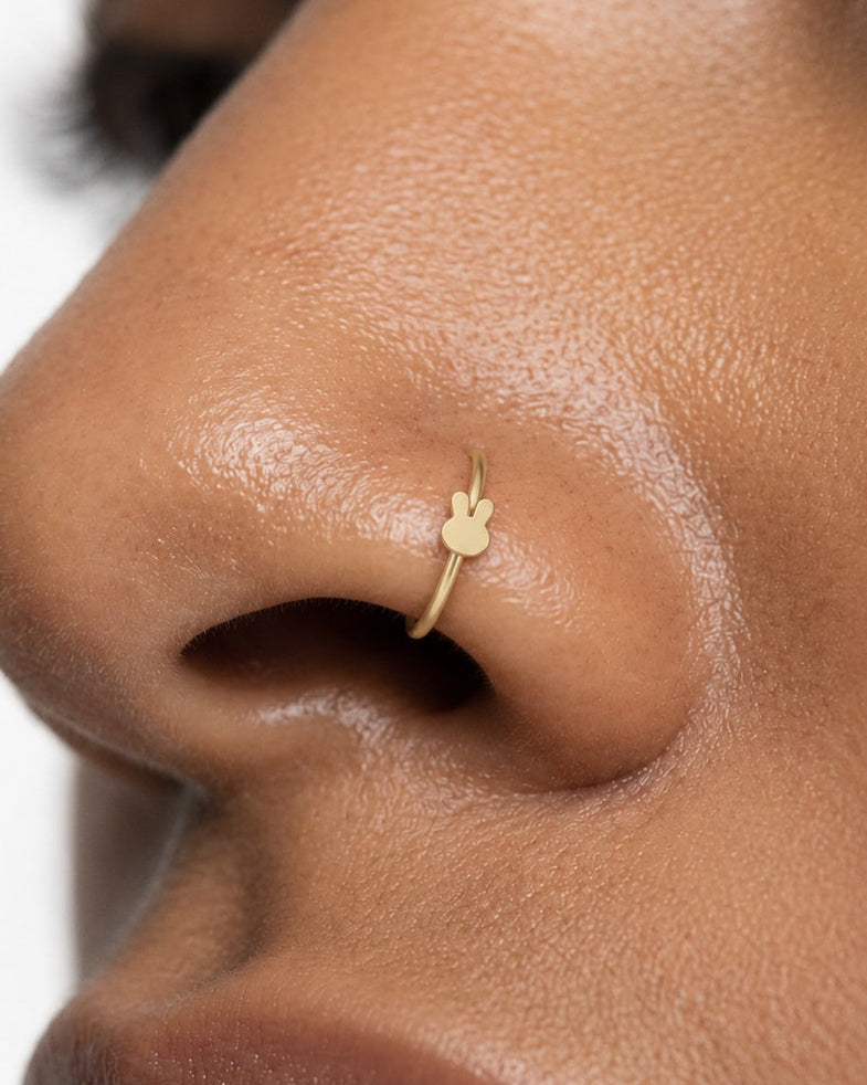 Two little ears, one playful detail. This 14ct solid gold rabbit nostril ring pairs an approximately 3mm polished bunny-head silhouette with a smooth seamless hoop. Upright ears with rounded tips and a softly curved face give the motif its character, with no engraved features or gemstones.
Handmade to order in yellow, white or rose gold, with inner diameters from 6 to 10mm and a choice of 18G (1.0mm) or 20G (0.8mm). Both the rabbit motif and hoop are solid gold and nickel-free, designed for a fully healed n
