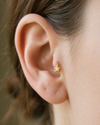 A crisp little star adds a bright celestial point to an otherwise minimal gold hoop. Made for fully healed tragus piercings, it adds a compact decorative detail without turning the piece into a dangling design. Handmade to order in 14ct solid gold, it fits naturally with bright, celestial and playful styling rather than reading as a generic plain hoop.
