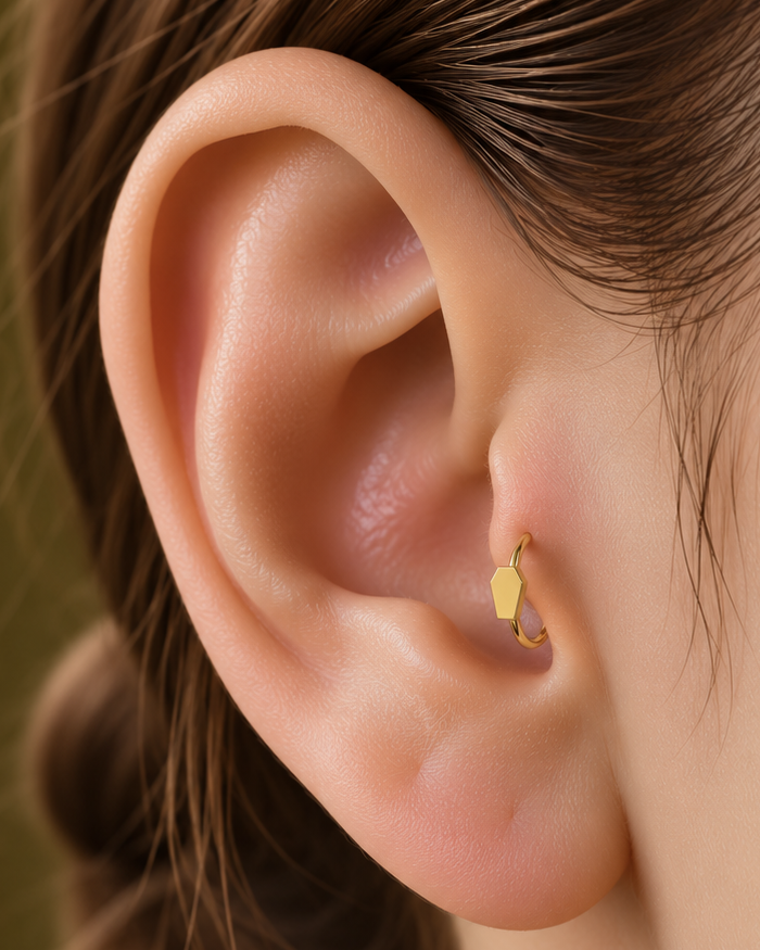 A small coffin motif gives the hoop a compact gothic accent with a clean polished finish. Made for fully healed tragus piercings, it adds a compact decorative detail without turning the piece into a dangling design. Handmade to order in 14ct solid gold, it fits naturally with gothic, alternative and Halloween-led styling rather than reading as a generic plain hoop.
